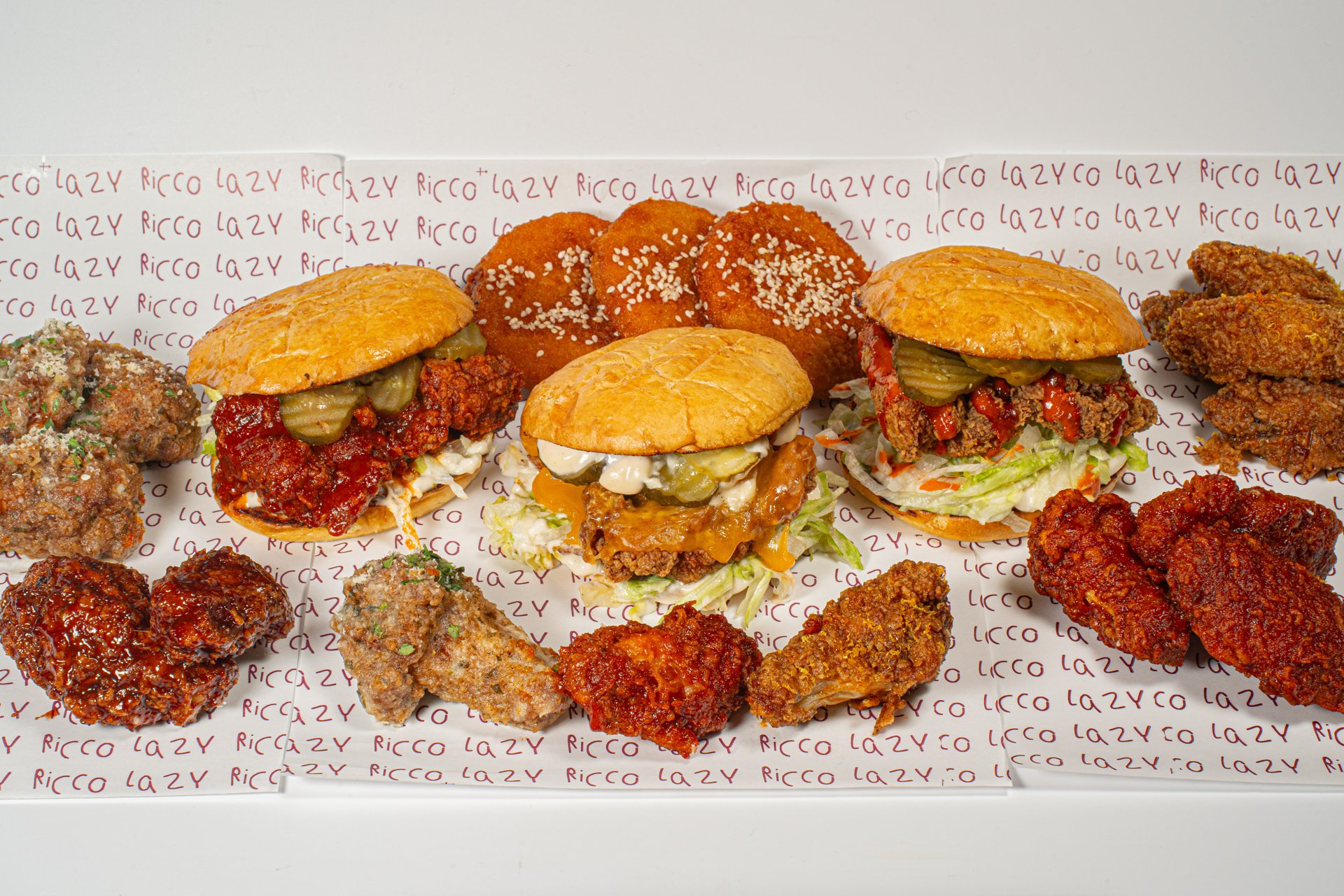 Lazy Ricco Chicken Burger in goldenen Brötchen, Wings mit verschiedenen Saucen und Beilagen